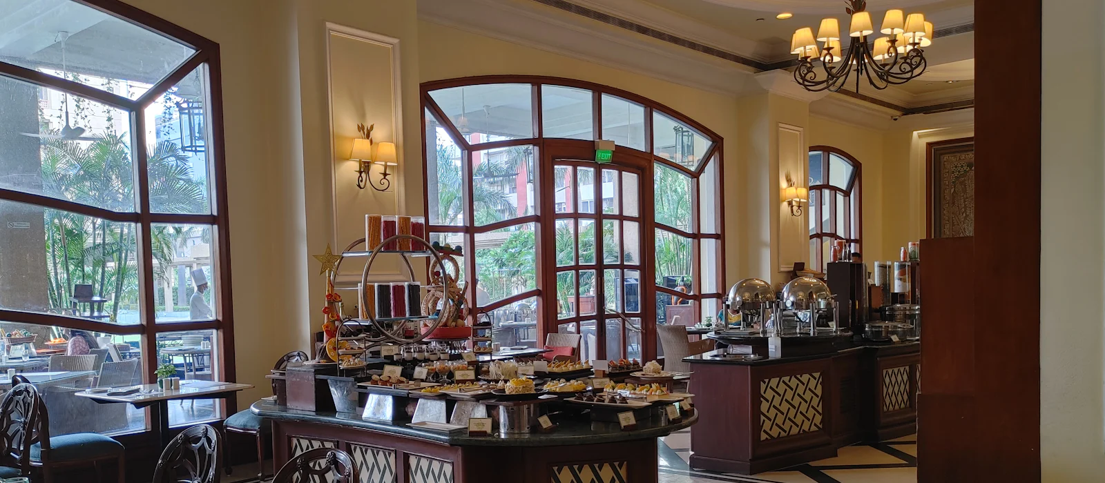 Hotel banquet hall with arched windows, chandeliers, and a buffet display.