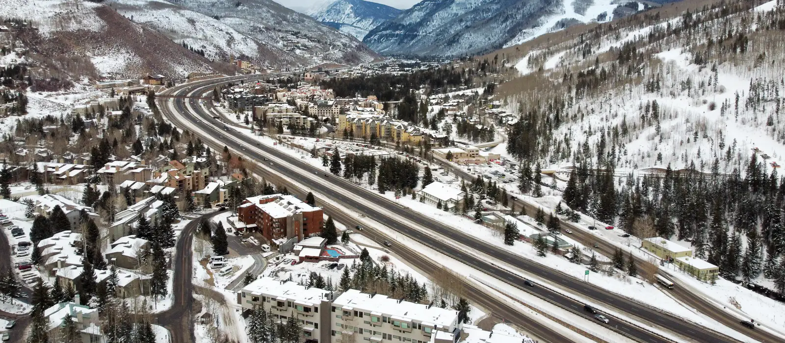 Aerial view of Interstate 70 running through the snowy Vail valley below the ski terrain.