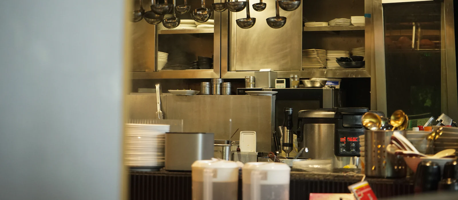 Busy restaurant kitchen with utensils hanging above stainless prep stations.