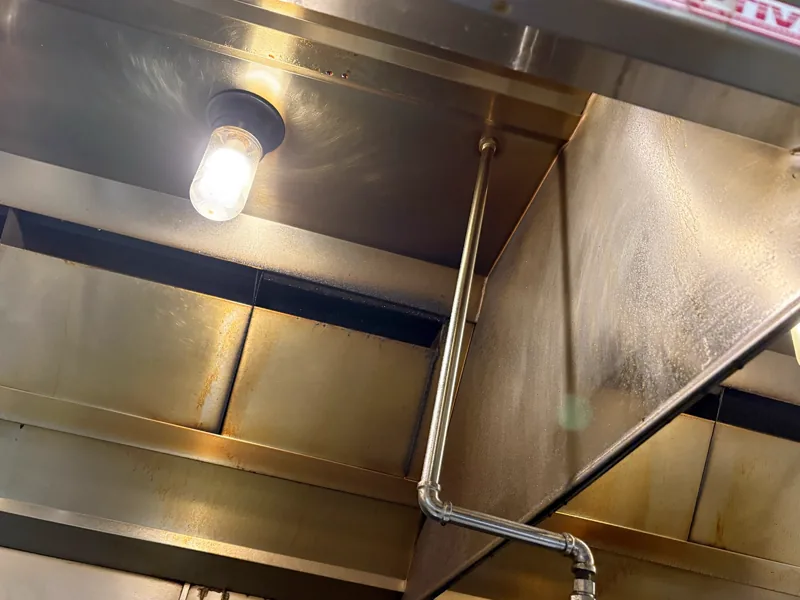 Hotel hood plenum before cleaning, grease spatter on the interior panels and filter track, Denver.