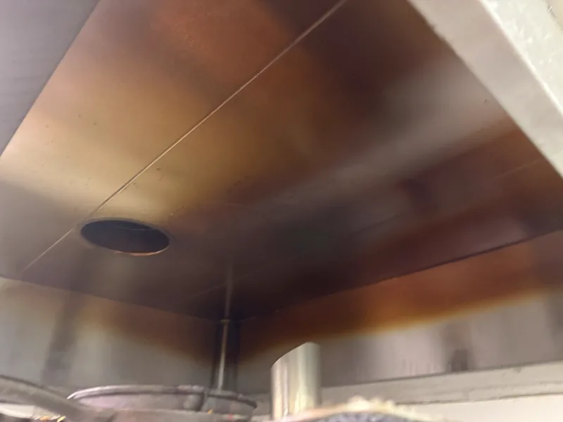 Restaurant hood plenum before cleaning, panels stained brown with baked grease, Denver.