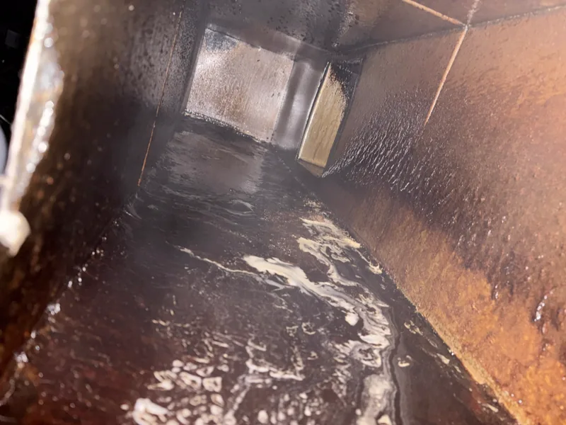Entertainment venue exhaust duct before cleaning, grease-coated walls and suds on the floor, Centennial.
