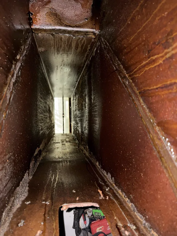 Hotel kitchen exhaust duct before cleaning, walls coated brown with grease, Cheyenne, Wyoming.