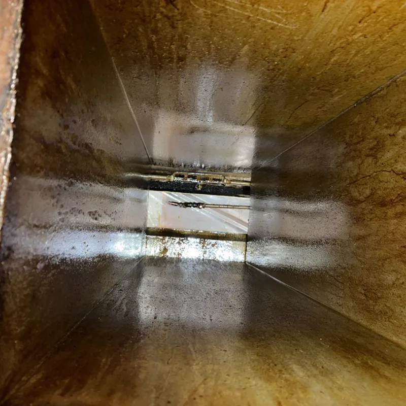 Restaurant exhaust duct before cleaning, brown grease deposit on the interior walls, Denver.