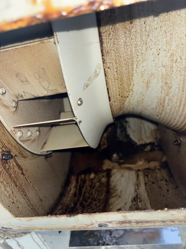 Stadium exhaust fan housing before cleaning, thick brown grease on the inner walls, Denver.